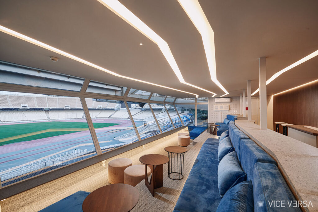 Renovated OAKA Presidential Suite lounge with blue sofas and views of Athens Olympic Stadium