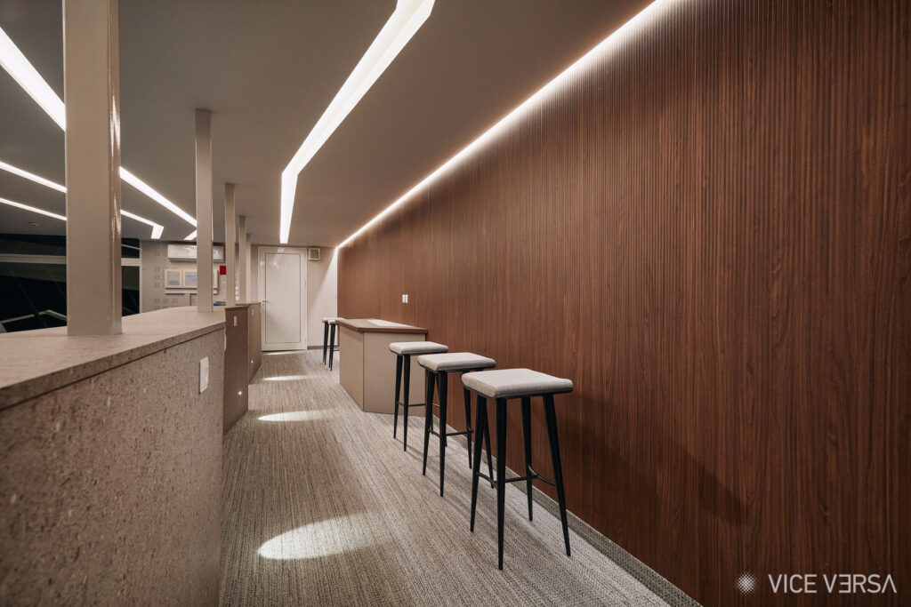 OAKA Presidential Suite interior with walnut wall panels, bar stools and linear ceiling lighting