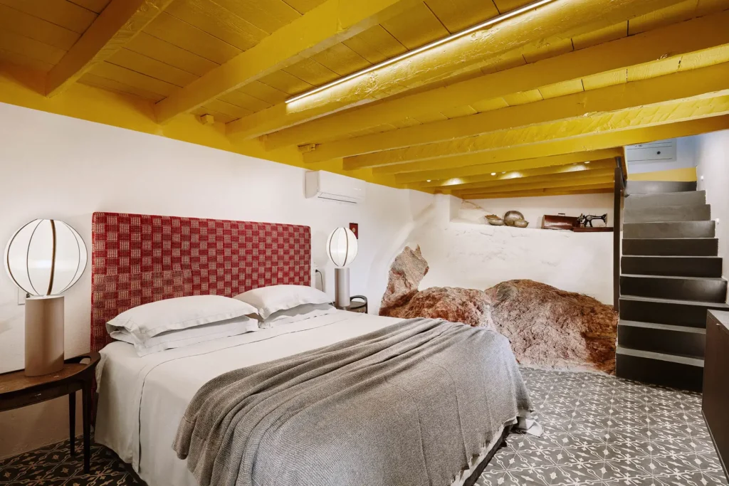 Guest room with yellow timber ceiling and linen bedding at The Monk Leros