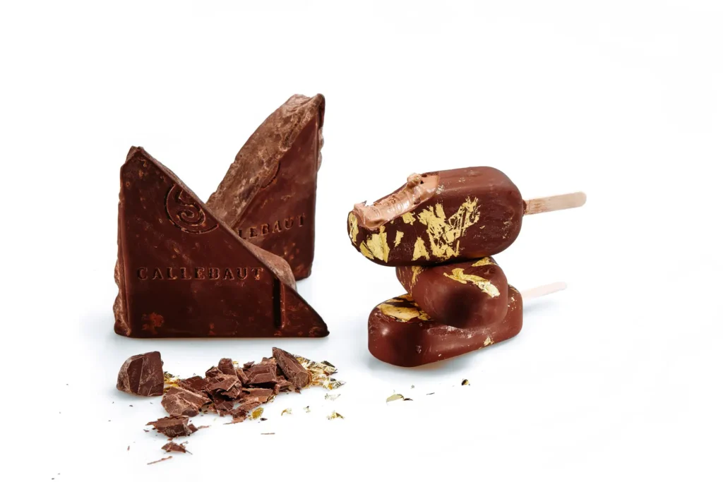 Callebaut ice cream sticks decorated with gold leaf beside a block of chocolate