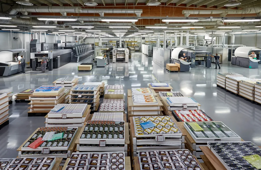 Corporate Photography for factories showing a wide production-floor view with printed sheets arranged on pallets