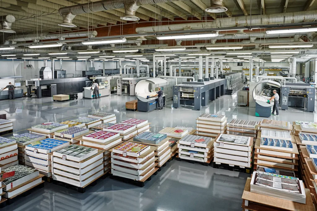 Karydakis printing production floor with operators, machinery and printed sheets stacked on pallets