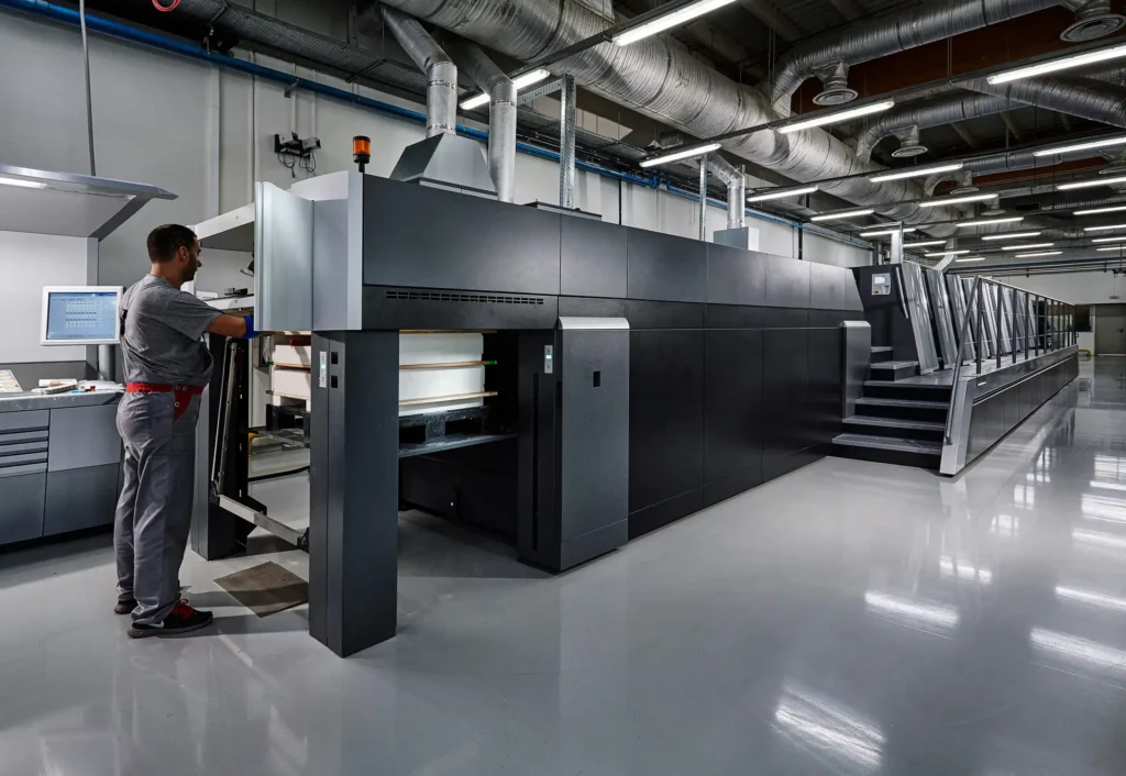 Operator working beside a large printing press at the Karydakis printing facility