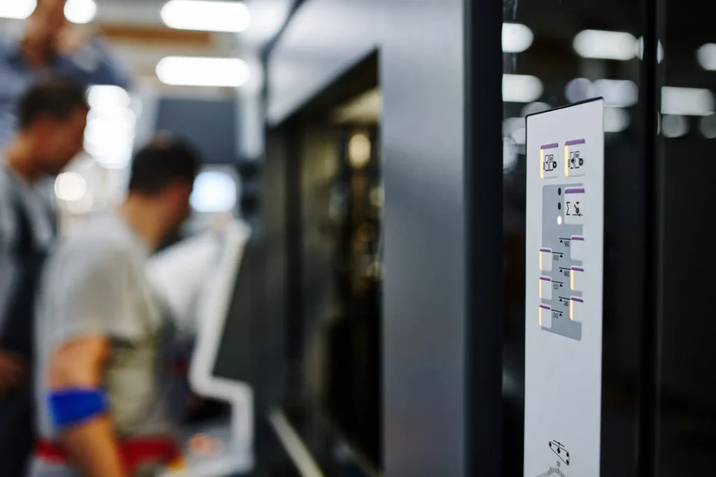 Corporate Photography for factories showing a printing press control panel with operators blurred in the background