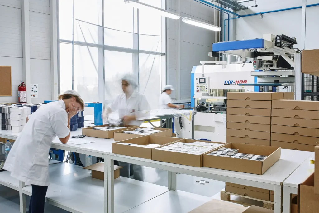 Workers inspecting and packing printed materials at tables in the Karydakis printing facility