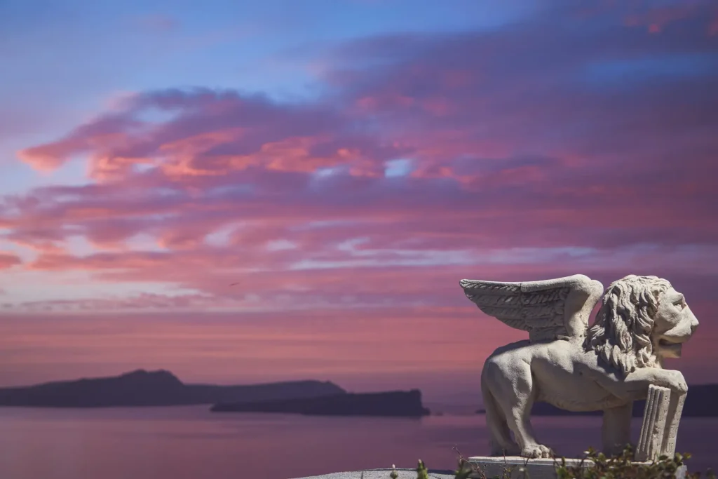 Sunset view of Palia Kameni from the villa terrace with a sculpture in the foreground