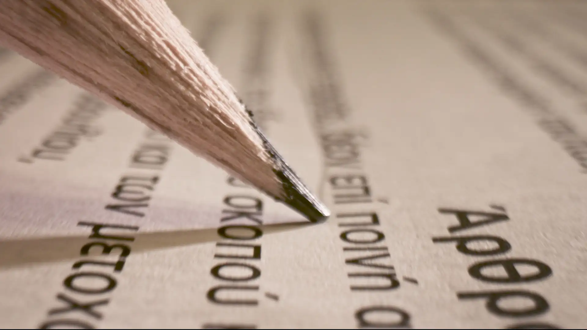 Macro close up detail of a pencil marking a Greek passage in an old paper book